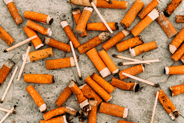 Cigarettes, matches and cigarette butts are scattered on the asphalt and road. Smoking is harmful...