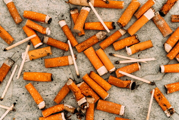Cigarettes, matches and cigarette butts are scattered on the asphalt and road. Smoking is harmful to human health.