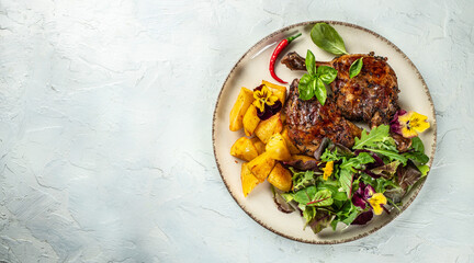 Roasted duck leg with potatoes on a light background top view. copy space