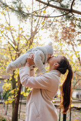 Fototapeta premium Young mother kiss her little boy at the autumn park