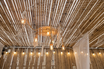 Hanging light bulbs by brown rope on bamboo ceiling in cafe