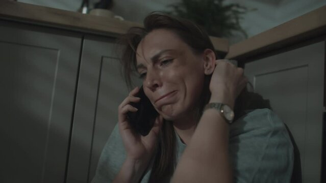 Medium close up of crying woman calling her friend after traumatic event sitting on floor at homeMedium close up of crying woman calling her friend after traumatic event sitting on floor at home