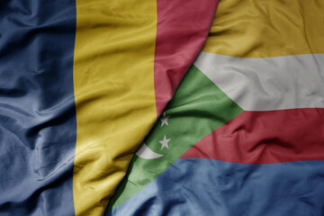 big waving national colorful flag of comoros and national flag of chad .