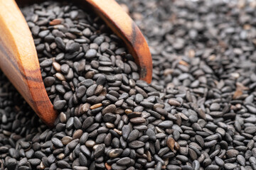 Wooden scoop in the heap of black cumin seeds. Food background.