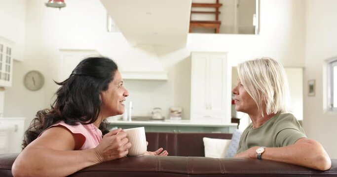 Angry diverse senior women arguing on sofa in sunny living room, slow motion