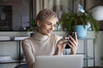 Happy female business leader, businesswoman, office employee using smartphone at workplace, texting, reading message, chatting online, browsing internet, social media. Manager making video call