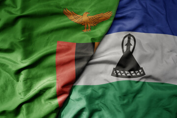 big waving national colorful flag of lesotho and national flag of zambia .