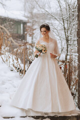 Obraz na płótnie Canvas Happy bride in a beautiful dress against the background of snowy mountains. Winter wedding. Portrait of a beautiful bride in a white fur coat and wedding dress