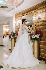 Elegant brunette bride poses in a white dress near the mirror. Portrait of the bride, wedding...