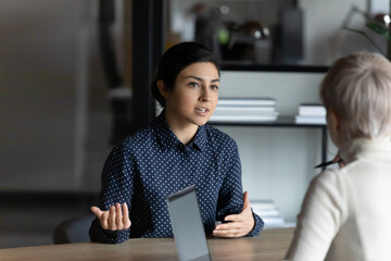 Serious female Indian job candidate speaking to employer, hr manager at job interview. Client and...