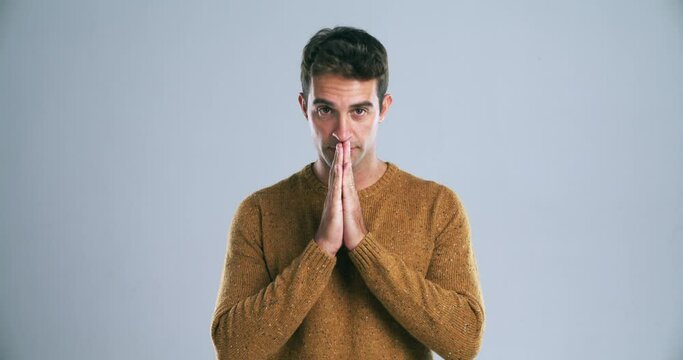 Young man, hands and praying for lucky draw, hope or faith isolated against a gray studio background. Portrait of handsome male person or model in blessing, pray or hoping for good luck on mockup