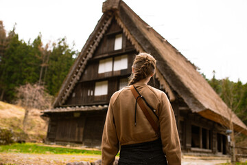 Frau mit braunem Zopf läuft vor japanischem traditionellen Gebäude