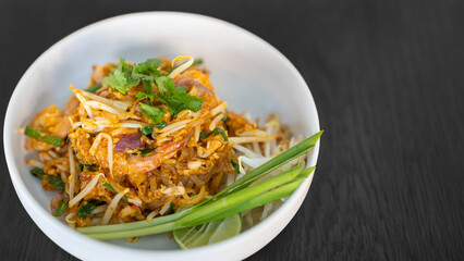 Pad thai coriander on top juicy creamy tasty delicious world popular. Thai famous food menu closeup in bowl on black wood table.