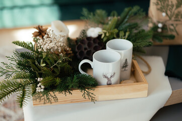 Wooden tray and two white mugs on the table, near the Christmas decor. Cozy morning. Winter mood at home. Christmas mood