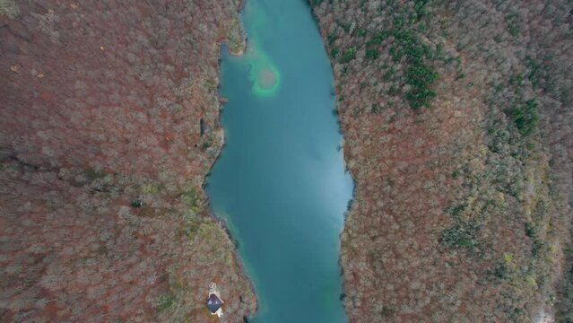 Aerial view of Montenegro Biograd Lake autumn colors and defoliated trees wooden pier and clouds with boats