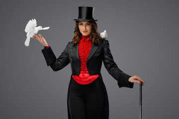 Mystical performance, female magician and white doves on gray background