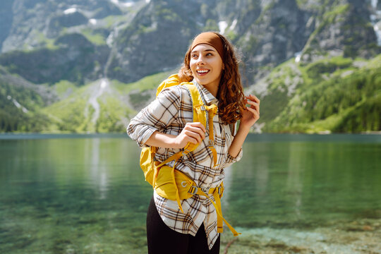 Young woman traveler with a bright hiking backpack on a high-mountain lake. The image of travelers. Adventure, vacation concept. Active lifestyle.