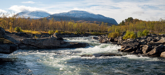 River flows in the vast landscape of Swedish Lapland on a sunny autumn day