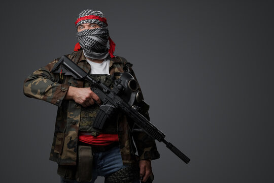 Middle Eastern radical fanatic soldier donning a white keffiyeh and camouflaged field uniform, armed with an automatic rifle, against a gray background