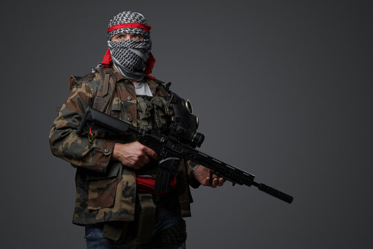 Middle Eastern radical fanatic soldier donning a white keffiyeh and camouflaged field uniform, armed with an automatic rifle, against a gray background