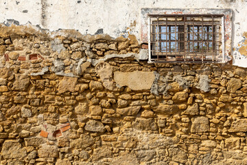 Fototapeta na wymiar Setubal, Portugal. 14 August 2023. Closeup pattern of surface brick wall concrete plaster for vintage background. Colors ocher, white, grey. Window left.