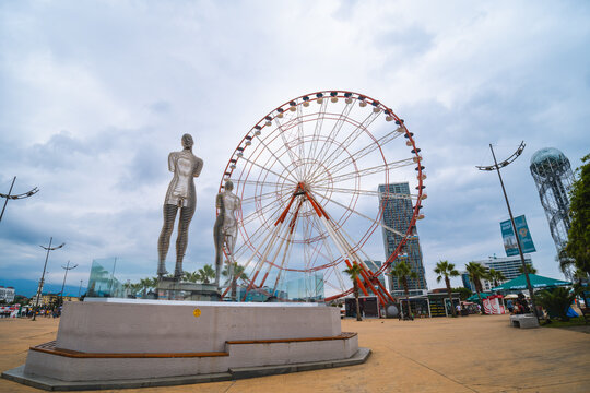 Batumi, Georgia - August 13 2021: Ali & Nino Statue and Ferris wheel on embankment of Batumi at sunny day
