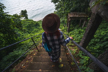 A woman in a wide hat walks among coastal thickets of bamboo and wild grapes. The way to the wild Hydrangea beach. Tsikhisdziri Georgia