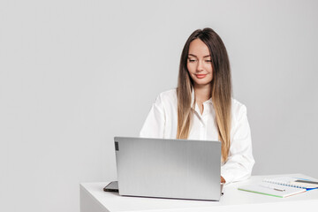 business lady sitting at table with laptop and phone isolated on white background in studio