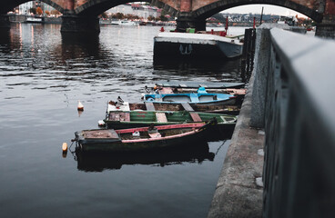 Naklejka premium Photo of boats on the Vltava river in Prague Czechia at the evening. Colorful vessels on the river in city - dark urban photo.