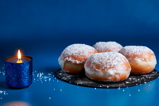 Hanukkah donuts with powdered sugar on a blue background. The concept and background of the Jewish holiday of Hanukkah. Copy space. 