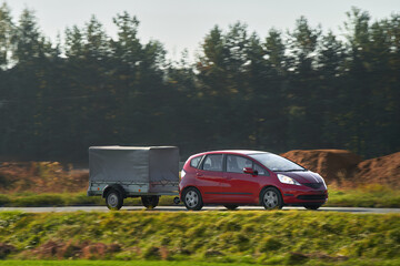 A Car and a Rental Trailer on a Curvy Road. A Smart Way to Move Your Stuff. Transporting Cargo with...
