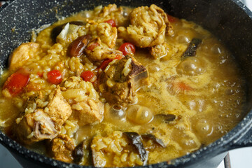 Braised eggplants with meat and rice in Israeli spices in a cast-iron high frying pan close-up.