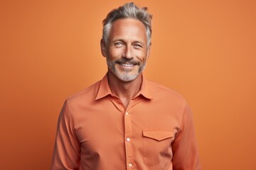 Obraz premium Portrait of a glad man in his 50s sporting a versatile denim shirt against a pastel orange background. AI Generation