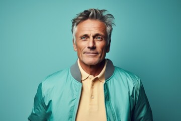 Fototapeta premium Portrait of a blissful man in his 50s wearing a trendy bomber jacket against a pastel teal background. AI Generation