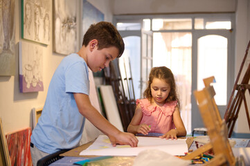Boy and girl drawing, learning art in workshop. Kids entertainment and development of creative skills in art gallery