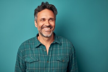 Portrait of a glad man in his 40s wearing a comfy flannel shirt against a soft teal background. AI Generation