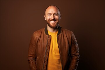 Obraz premium Portrait of a grinning man in his 30s wearing a trendy bomber jacket against a soft brown background. AI Generation