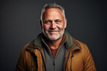 Obraz premium Portrait of a grinning man in his 50s dressed in a water-resistant gilet against a soft brown background. AI Generation