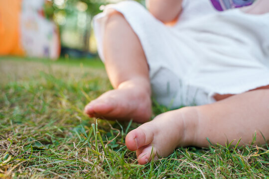 The feet of a little child baby without shoes on the grass