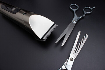 Hairdressing scissors and Machine for a hairstyle on black background. Hairdresser salon equipment concept, premium hairdressing shears. Accessories for haircut. Men beauty and health concept.