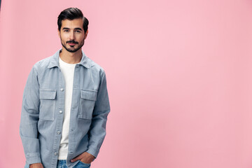 Obraz premium Portrait of a stylish brunette man with a beard beautiful smile on a pink background in a white T-shirt and jeans smile and joyful emotion on his face, copy space
