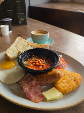 Full English breakfast with beans and sausage served on wooden table