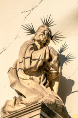 Fototapeta na wymiar Kneeling Jesus with thorny crown halo casting shadow on cracked wall