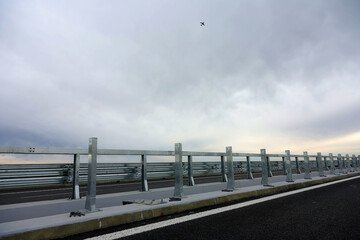 Road metal bump mounted on a new highway motorway after construction and repair in a cloudy day with a aiplane above. Road elements mounted for safety traffic.