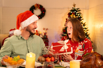 Obraz na płótnie Canvas happy couple wife open gift box surprise from her husband while celebrating christmas party in house, caucasian people big family celebrate festive holiday thanksgiving, X-mas eve together at home