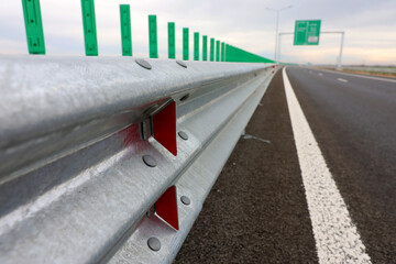 Road metal bump with red reflectors mounted on a new highway motorway after construction and repair in a cloudy day. Road elements mounted for safety traffic.