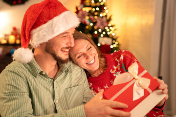 Obraz na płótnie Canvas happy couple wife open gift box surprise from her husband while celebrating christmas party in house, caucasian people big family celebrate festive holiday thanksgiving, X-mas eve together at home