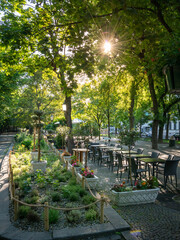 Empty café tables in park at sunrise in Bratislava old town promenade