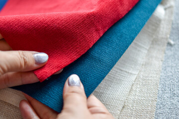 Close up view, Human hand selecting fabrics material samples for making furniture and home...