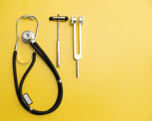 Stethoscope, Neurological Hammer and Tuning Fork C 128 on Yellow Background with Space for Text